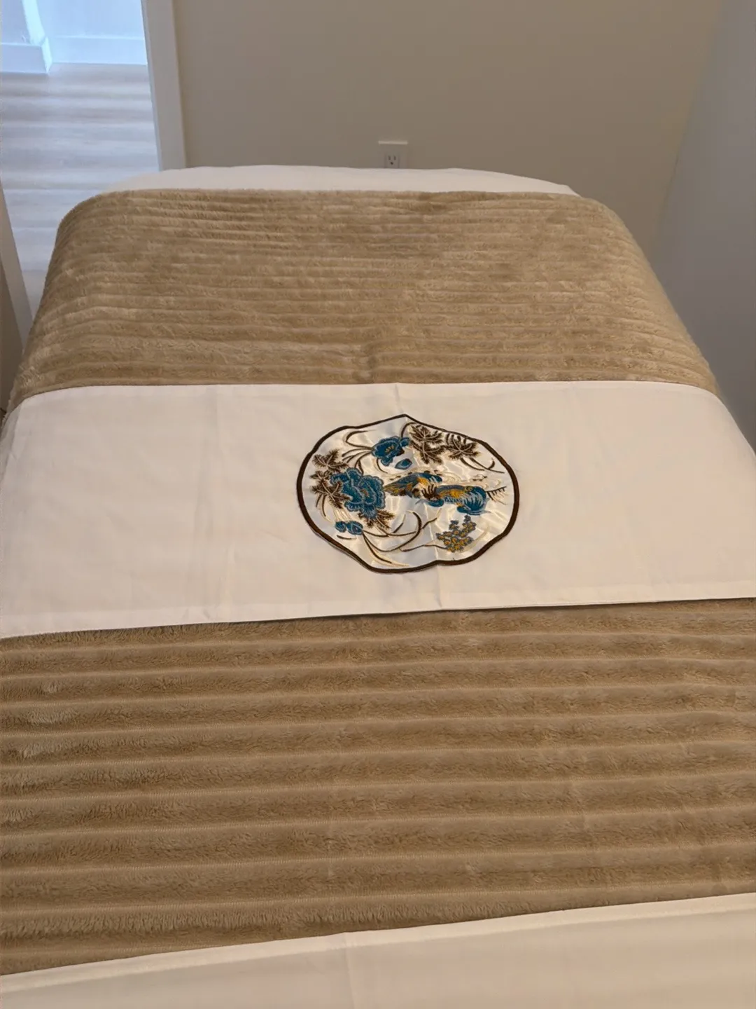 Embroidered table runner detail on a massage table at Harbor Wellness